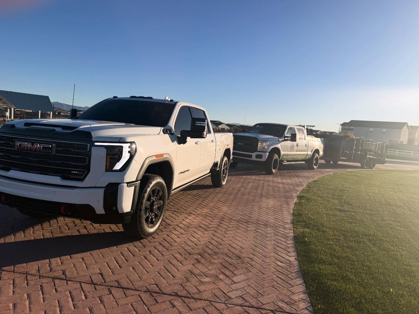 K&O Landscaping trucks and trailer parked on a paver driveway beside a finished lawn