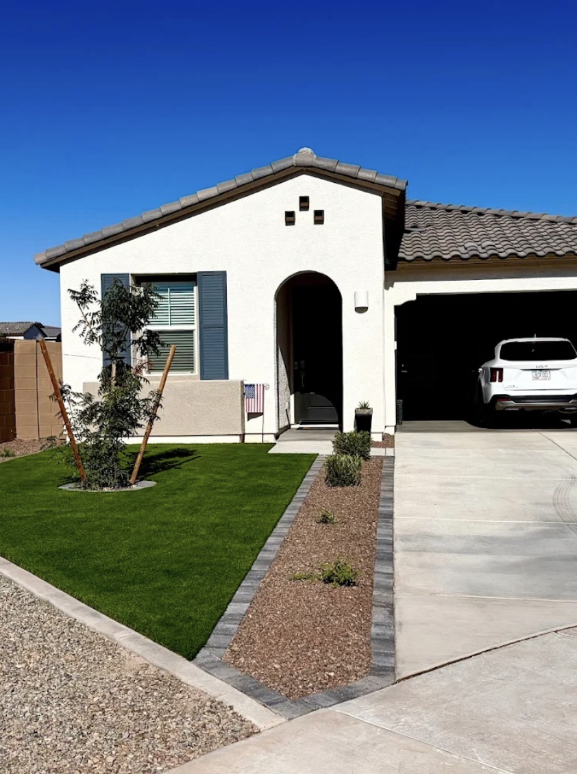 Front yard install with a new lawn, paver-edged rock bed and young tree