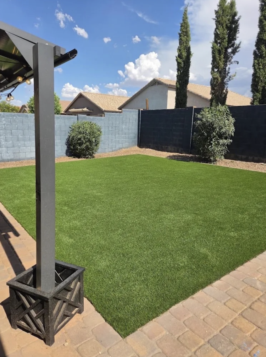 Backyard turf lawn bordered by pavers and privacy wall